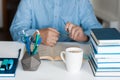 Close-up hands of the teacher man is preparing for the lesson: reading a book and making notes at the table, next to a pile of Royalty Free Stock Photo