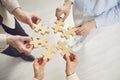 Close up hands of team assembling jigsaw wood puzzle, joining pieces to search idea, right solution Royalty Free Stock Photo