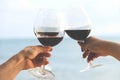 Hands holding red wine glasses on the beach Royalty Free Stock Photo