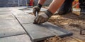 Close up on the hands and tools of an expert workman laying patio slabs in garden makeover. Created with AI Royalty Free Stock Photo