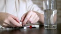 Close up of hands touching pills. The concept of health care, vitamin deficiency. woman sorts pills sitting at the table