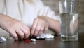 Close up of hands touching pills. The concept of health care, vitamin deficiency. woman sorts pills sitting at the table