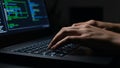 Close-up of hands typing on laptop keyboard with code on screen Royalty Free Stock Photo