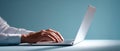 Close-up of hands typing on a laptop keyboard with a minimalist blue background and soft lighting Royalty Free Stock Photo