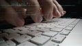 Close-up of Hands Typing on a Laptop Keyboard with Programming Code Overlay in a Dark Environment for Technology and Royalty Free Stock Photo