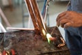 Close up on hands of unknown industrial worker plumber with central heating copper pipes welding using gas torch or blowtorch at Royalty Free Stock Photo