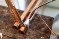 Close up on hands of unknown industrial worker plumber with central heating copper pipes welding using gas torch or blowtorch at Royalty Free Stock Photo