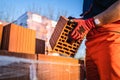 Close up on hands of unknown man construction worker taking clay brick orange hollow clay block for building at warehouse or Royalty Free Stock Photo
