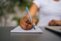 Close-up hands of unrecognizable African-American woman writing down important work information in notebook sitting at Royalty Free Stock Photo