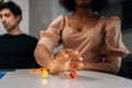 Close-up hands of unrecognizable African American young woman throwing dice playing in board game with diverse friends