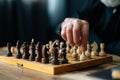 Close-up hands of unrecognizable bearded chess player performing move with pawn piece on wooden chessboard, selective