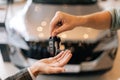 Close-up hands of unrecognizable dealer male giving new car key to customer man in business suit on blurred background Royalty Free Stock Photo