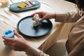 Close-up hands of unrecognizable female artisan putting on table ready to use handmade candle in shape of beautiful body