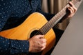 Close-up hands of unrecognizable guitarist man playing on acoustic guitar sitting at desk at home. Royalty Free Stock Photo