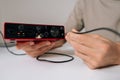Close-up hands of unrecognizable man connecting audio jack cable into red usb audio interface, preparing for home music Royalty Free Stock Photo