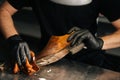 Close-up hands of unrecognizable shoemaker in black gloves applying cleaning foam on old light brown leather shoes.