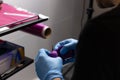 Close-up of the hands of unrecognizable tattoo artist wearing sterile blue gloves while preparing the machine for tattooing in a Royalty Free Stock Photo