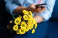 Close-up of hands of unrecognizable woman holding bouquet yellow chrysanthemums and using cell phone Royalty Free Stock Photo