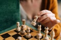Close-up hands of unrecognizable woman making chess move sitting at table in dark room, selective focus. Royalty Free Stock Photo