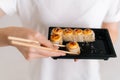 Close-up hands of unrecognizable young woman taking delicious sushi rolls with chopsticks on white isolated background Royalty Free Stock Photo