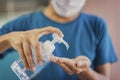 Close up of hands using antiseptic gel, alcohol gel to disinfect hands over a work desk in at home. Preventive measures during the