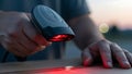 Close up of hands using a handheld barcode scanner with a bright red laser beam on a package Royalty Free Stock Photo