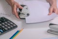 Close-up of hands using hole punch to staple documents in office