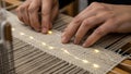 Close-up of hands weaving led strands into beige fabric on loom Royalty Free Stock Photo