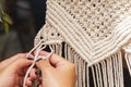 Close up Hands weaving macrame tapestry with beige thread