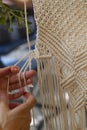 Close up Hands weaving macrame tapestry with beige thread
