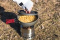 Close up hands of woman cooking pasta on wood burner in wild camping Royalty Free Stock Photo