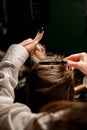 close-up of hands of woman hairdresser neatly fasten hair of female client with hairpin.