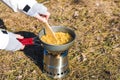 Close up hands of woman hiker cooking pasta on wood burner in wild camping Royalty Free Stock Photo