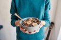 Close up of hands of woman holding homemade granola in a plate with nuts, honey, blueberries, banana and other natural Royalty Free Stock Photo