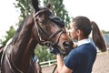 Close up hands of jockey woman hugging a horse. Young girl petting her horse in stable. Equine therapy concept. Love between Royalty Free Stock Photo