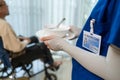 Close up hands of woman nurse at nursing home taking care of disabled senior elderly man on wheelchair. Therapist doctor serving f Royalty Free Stock Photo