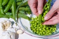 Close up of the hands of a woman shelling peas from the pod inside a glass bowl outdoors with sunlight Royalty Free Stock Photo