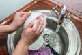 Close up hands of woman washing dishes in kitchen. Cleaning chores Royalty Free Stock Photo