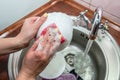 Close up hands of woman washing dishes in kitchen. Cleaning chores Royalty Free Stock Photo