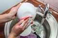 Close up hands of woman washing dishes in kitchen. Cleaning chores Royalty Free Stock Photo