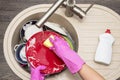 Close up hands of woman washing dishes in kitchen. Hands in red rubber gloves washing the dishes. Top view Royalty Free Stock Photo