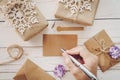 Close up of hands woman writing empty wishlist and christmas card on wooden table with xmas decoration