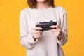 Close up of hands women playing video games e female holding joystick over yellow isolated background Royalty Free Stock Photo