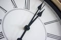 Close-up of the hands of a wooden wall clock with roman numerals.