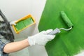 Close up of hands in working gloves painting a wall green with middle-sized roller Royalty Free Stock Photo