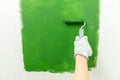 Close up of hands in working gloves painting a wall green with middle-sized roller Royalty Free Stock Photo