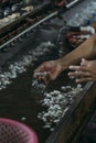 Close-up of hands working in silk worm factory processing cocoons with water sinks in Dalat Vietnam.