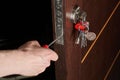 Close up of hands of young carpenter holding a screwdriver and fixing the lock of door. The man is standing in workwear Royalty Free Stock Photo