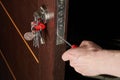 Close up of hands of young carpenter holding a screwdriver and fixing the lock of door. The man is standing in workwear Royalty Free Stock Photo
