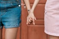 Close up of hands of young female couple holding each other hands, standing together in front of the door outdoors. LGBT Royalty Free Stock Photo